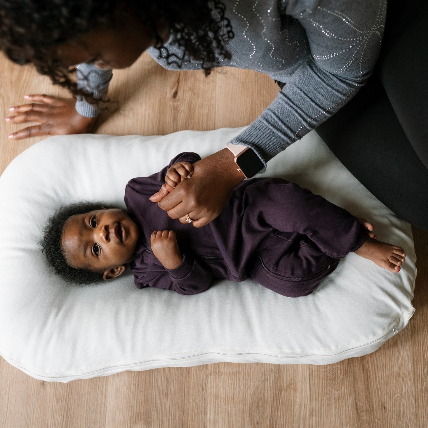 baby lying on a white cushion wearing footless ZippyJamz in Midnight Dreams solid colour