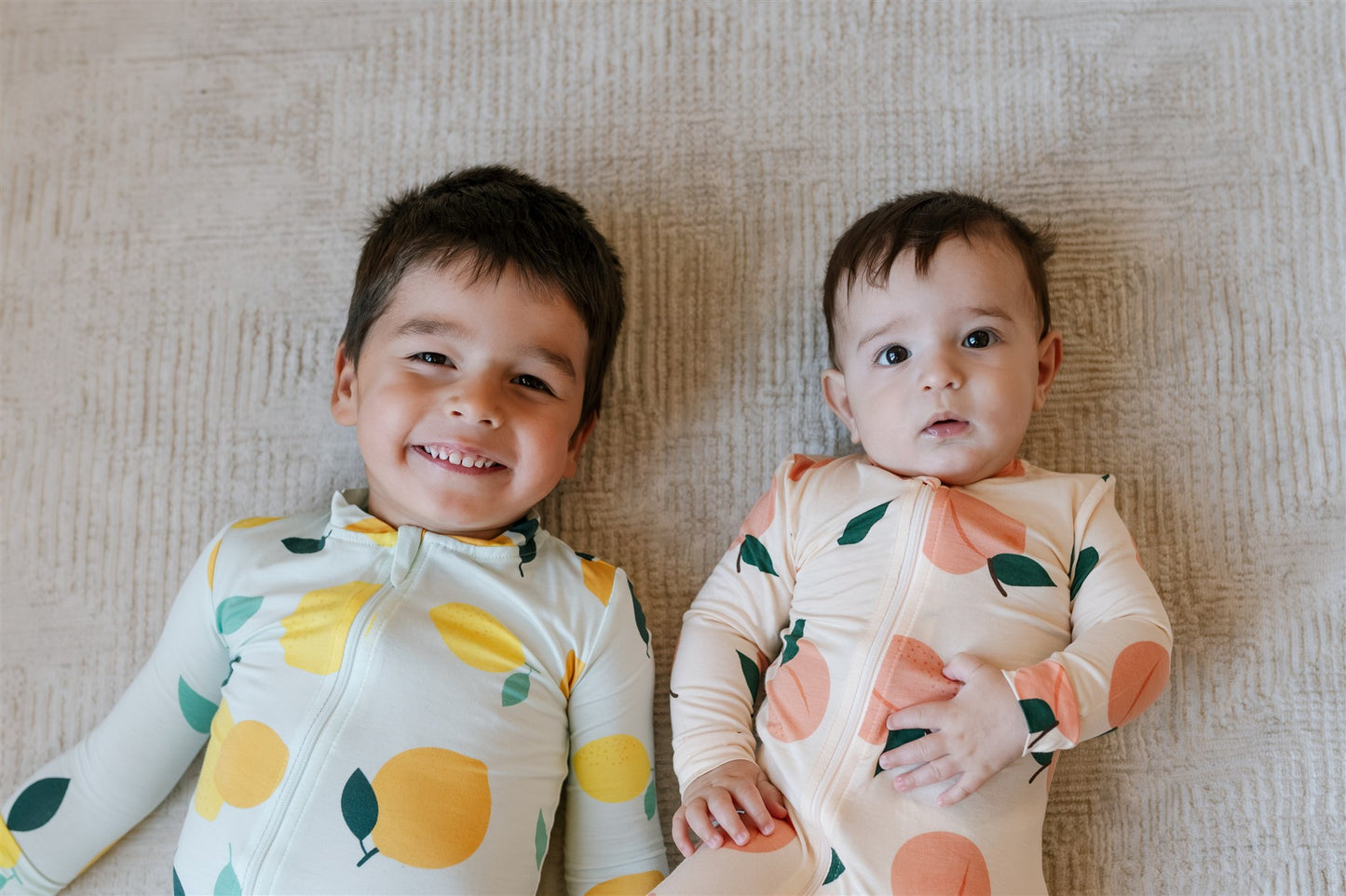 Two young children wearing ZippyJamz fruit patterned sleepers.