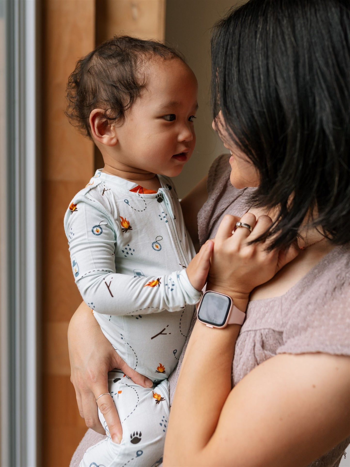 Woman holding a baby wearing bamboo baby pajamas in blue tents and tranquility pattern